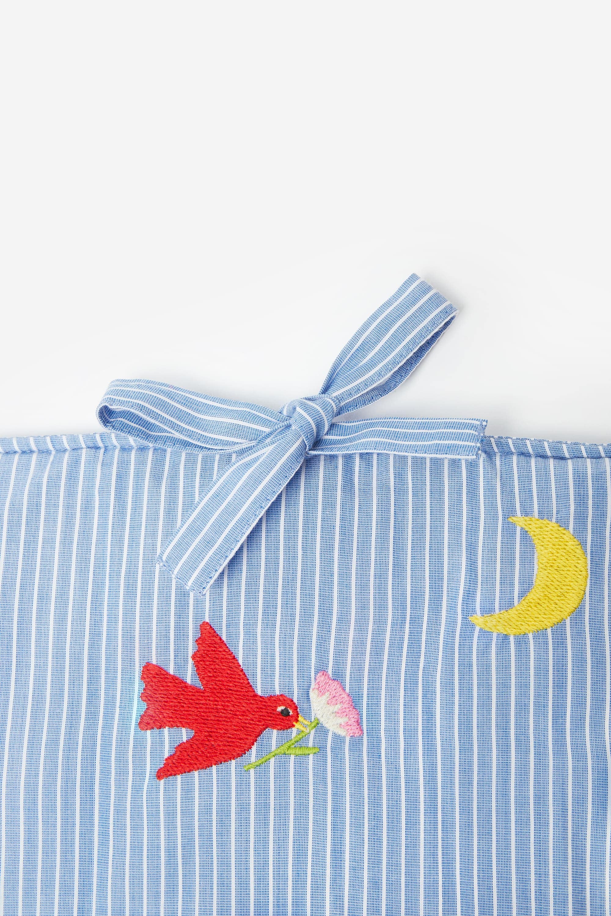 tour de lit 26 paradis en coton brodé design et réconfortant. Entièrement brodé avec notre motif iconique aux couleurs éclatantes sur du coton certifié oeko-tex, il met en scène l'oiseau et la fleur dans une composition joyeuse et ludique.