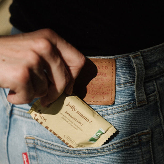 Femme tenant un snack gourmand Banana choc de Jolly mama et s'apprêtant à le déguster